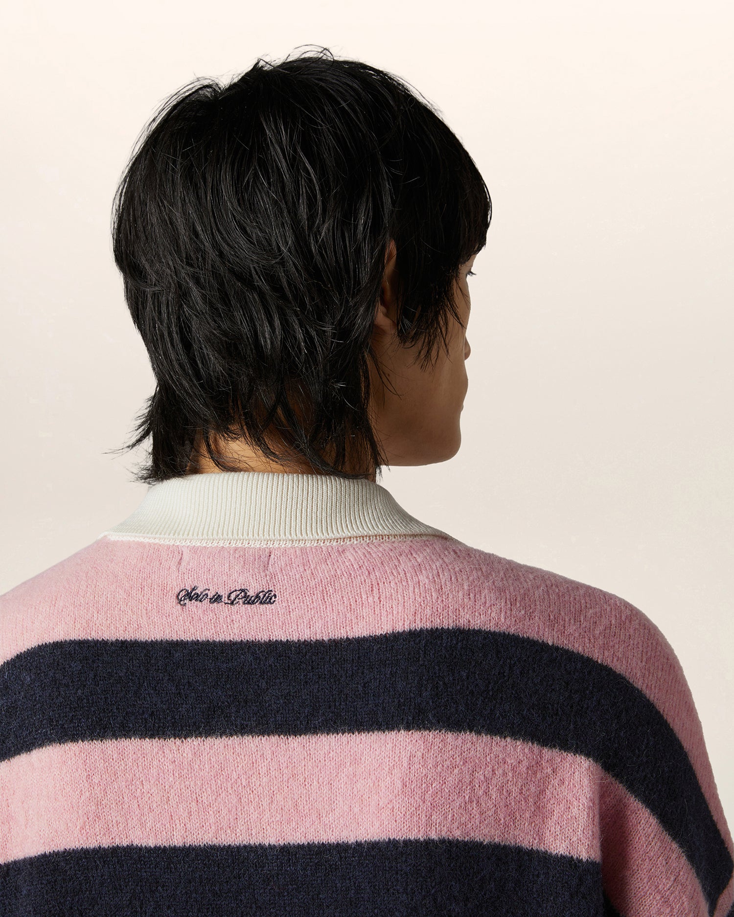 Close-up of embroidery at the back neckline on pink and navy Italian alpaca knit rugby top — luxury streetwear knitwear detail for men.